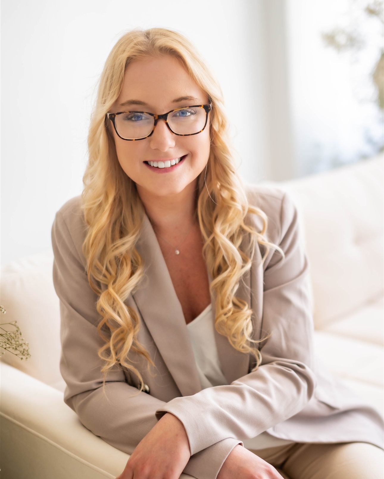 Hannah Lee, founder of Synovial Marketing, smiling with her arms resting on the back of a sofa